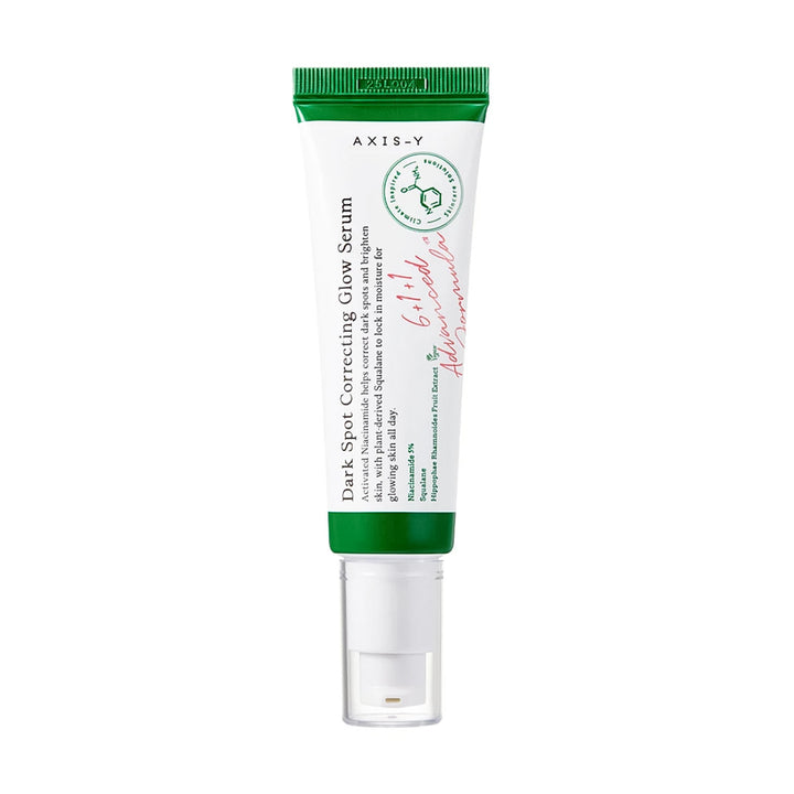 A tube of AXIS-Y Dark Spot Correcting Glow Serum with a white body, green cap and base, and a clear applicator cap, shown on a plain white background.