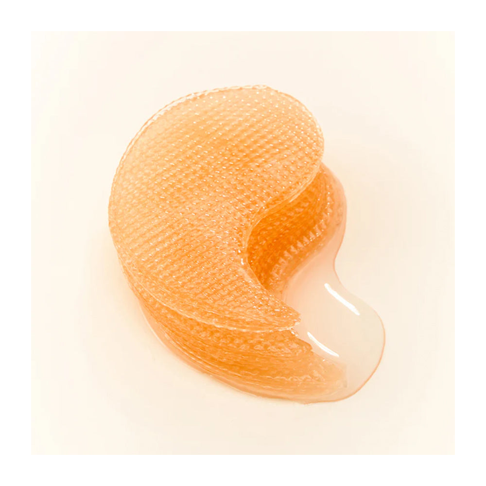 An orange translucent silicone eye patch with a textured honeycomb pattern on the top half and a smooth glossy bottom half, displayed on a clean off-white background.