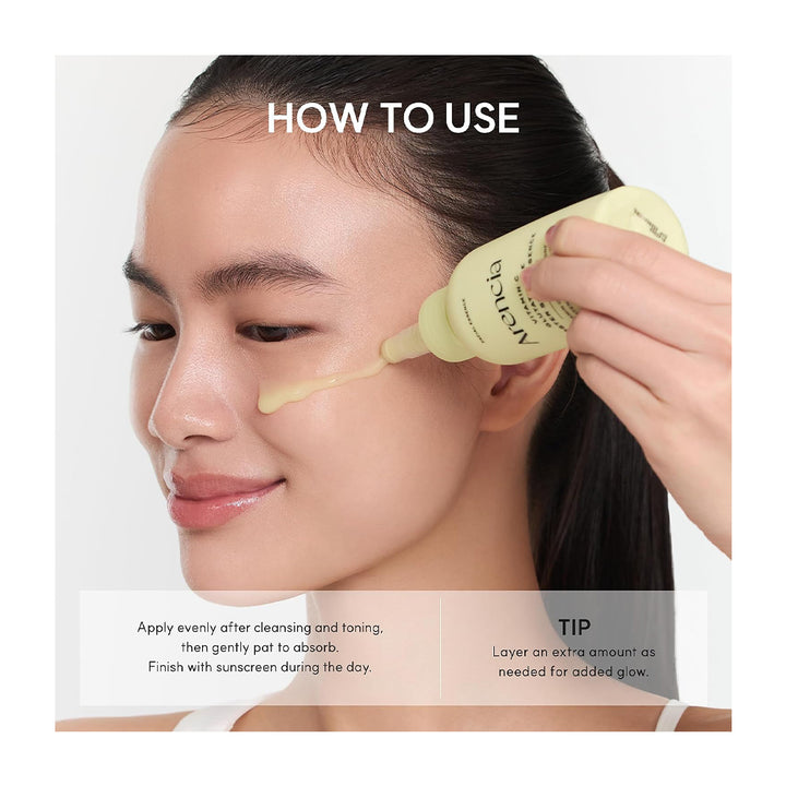 A woman applies a pale yellow skincare serum from a tube labeled &