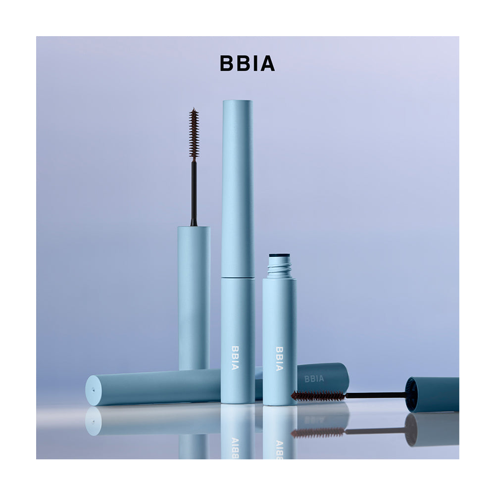 BBIA mascara set in a light blue color, featuring multiple tubes and a wand with a black bristle brush, arranged on a reflective surface against a soft lavender background.