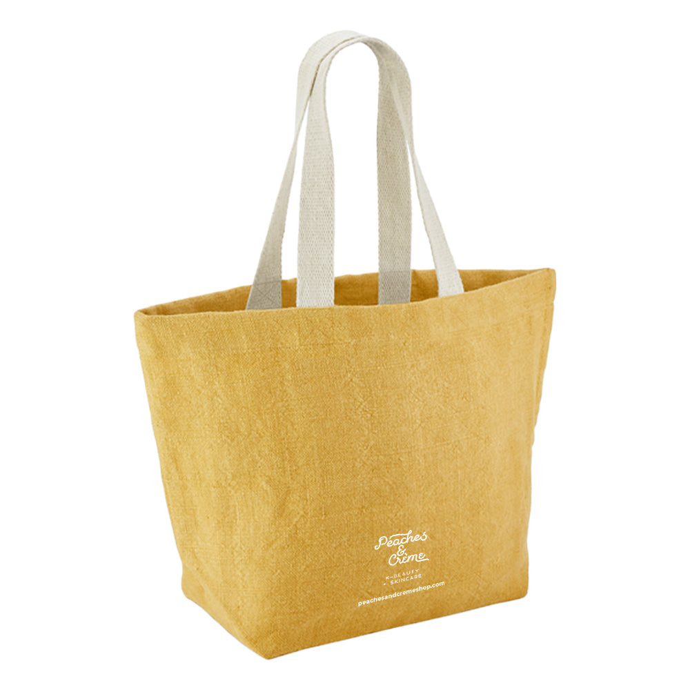 A mustard yellow canvas tote bag with light beige fabric shoulder straps and white embroidered &