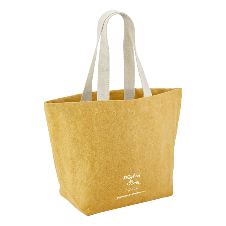 A mustard yellow canvas tote bag with light beige fabric shoulder straps and white embroidered &