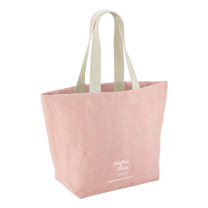 A dusty pink canvas tote bag with light beige fabric shoulder straps and white embroidered &