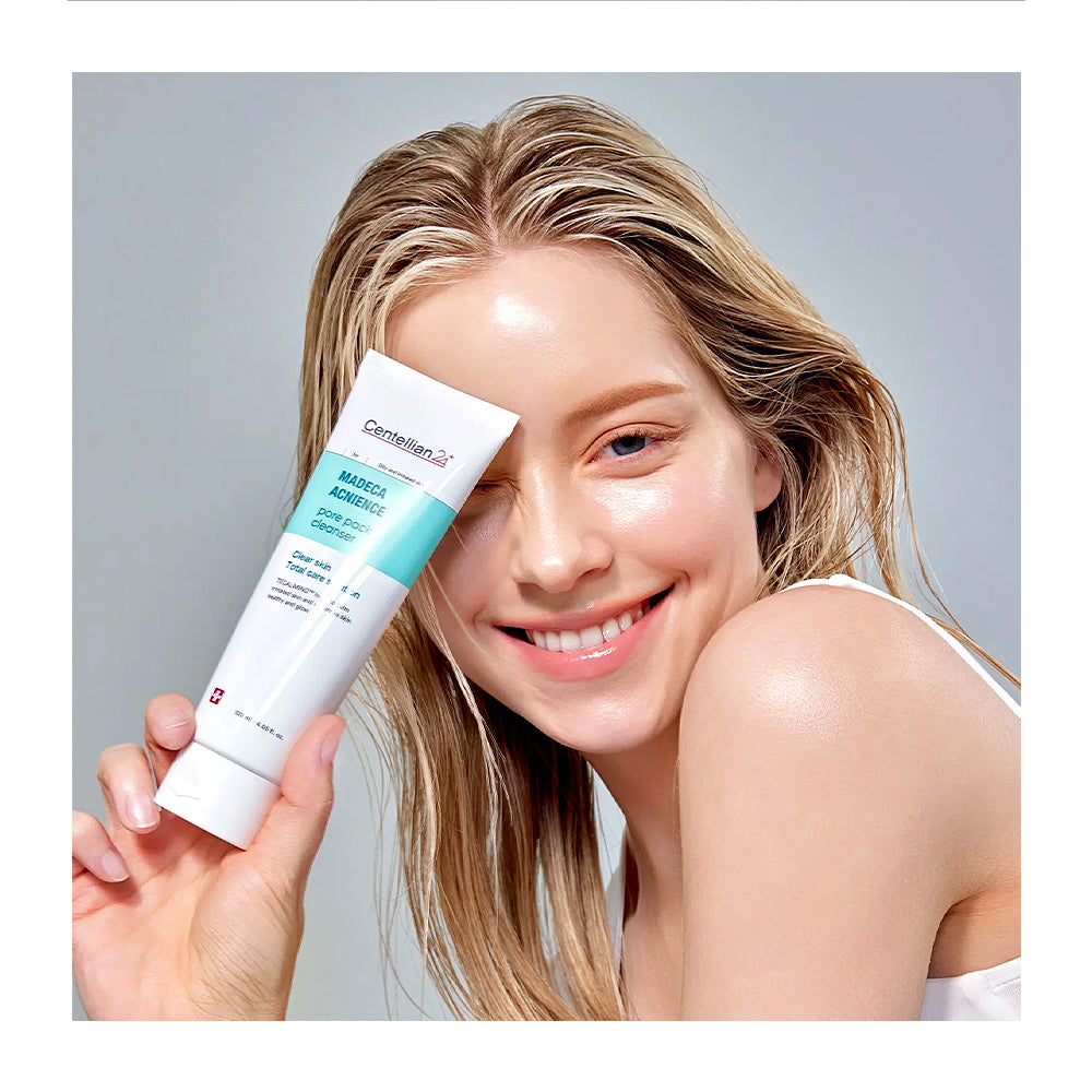Woman applying sunscreen cream to her face with a gray background