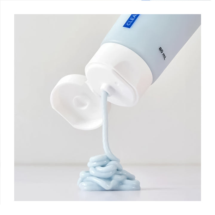 A light blue cosmetic tube with a white flip-top cap, shown dispensing a thick, pale blue cream onto a white surface against a clean white background.