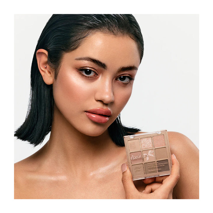 Woman holding a makeup palette with a neutral background