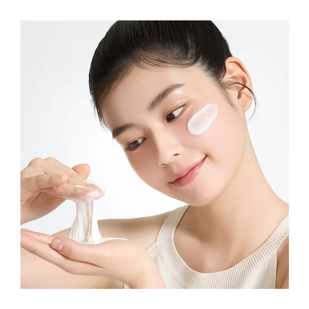 Woman applying cream to her face with a white background
