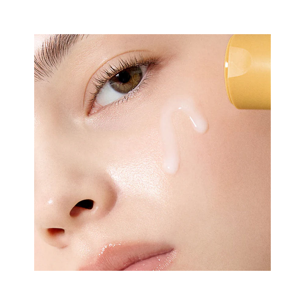 Close-up of a person applying cream to their face with a yellow applicator.