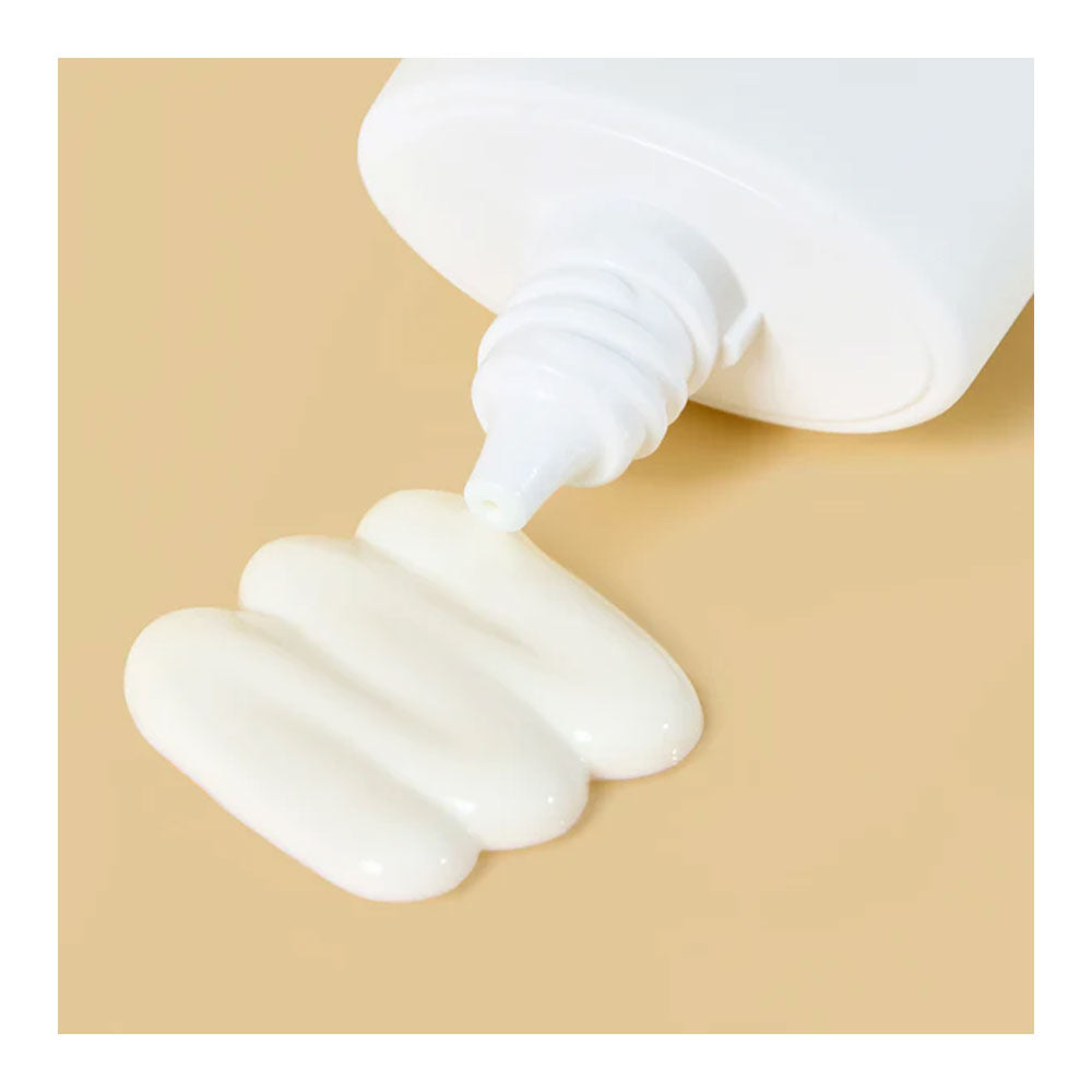 White cream being squeezed from a tube onto a beige background