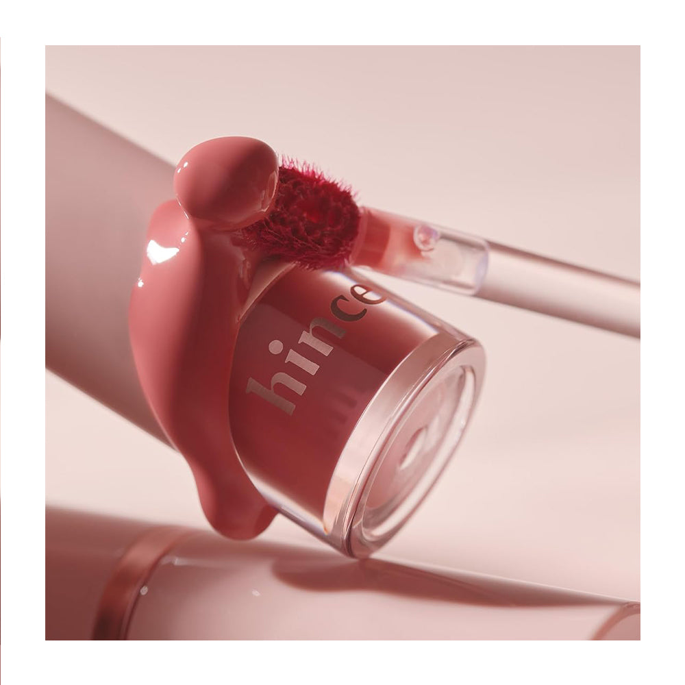 Pink lip gloss with applicator on a light pink background