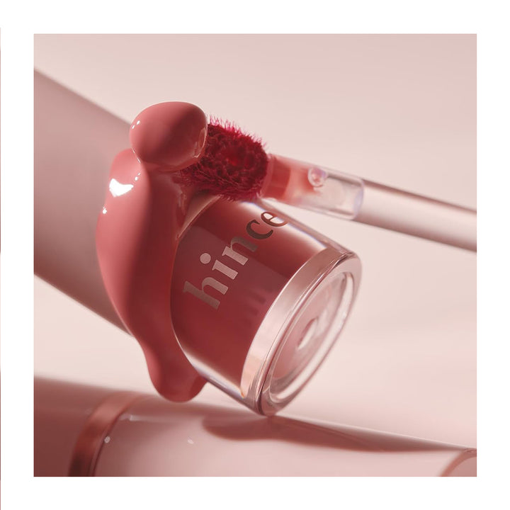 Pink lip gloss with applicator on a light pink background