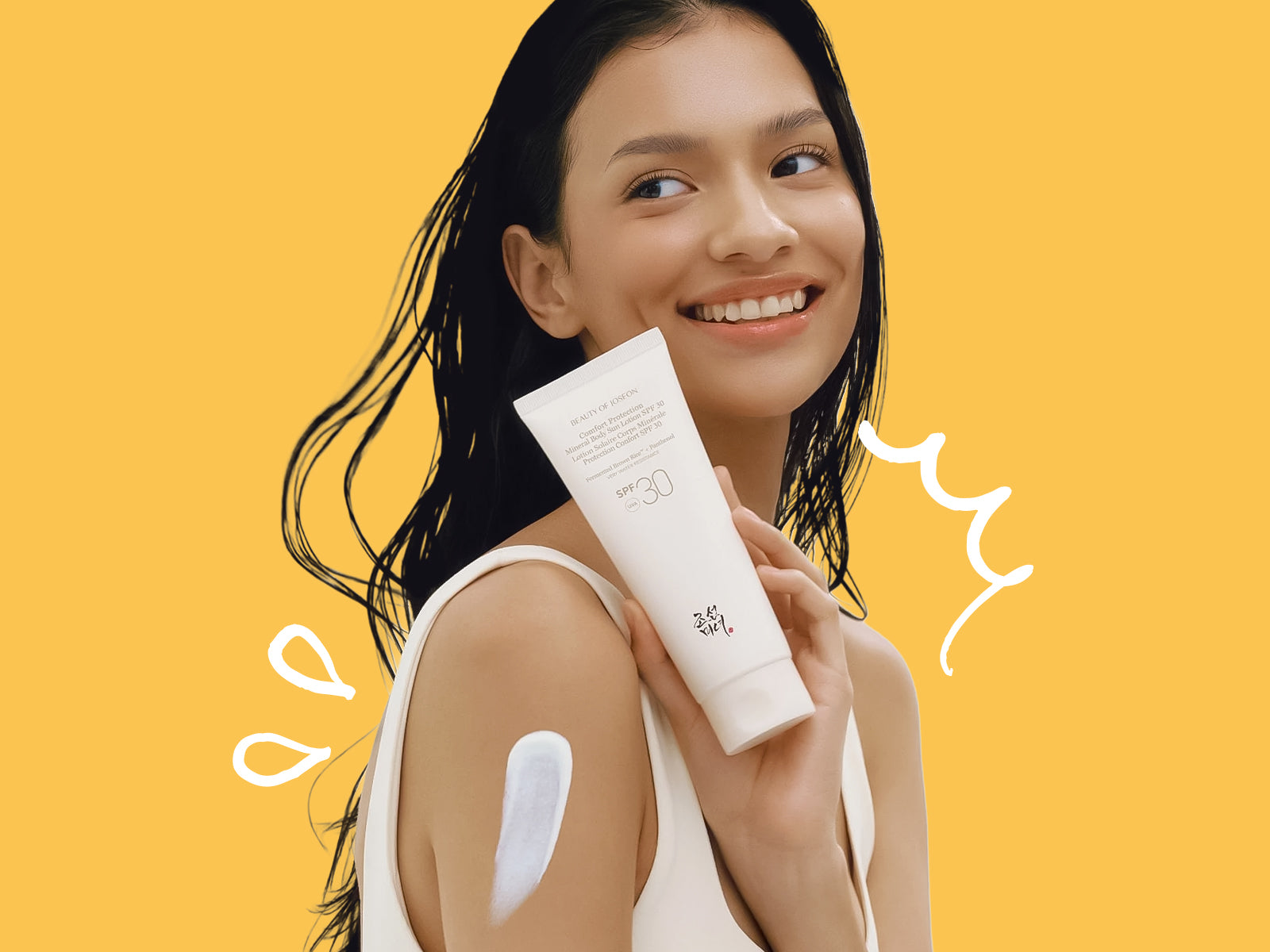 Woman holding a skincare product with a yellow background