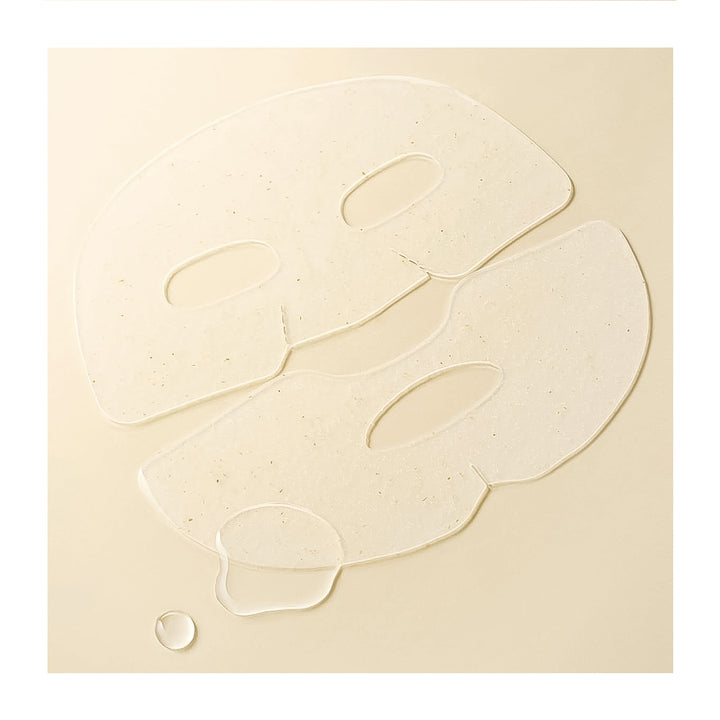 Two translucent, face-shaped sheet masks with embedded tiny specks, displayed on a warm beige background with a small droplet at the bottom left.