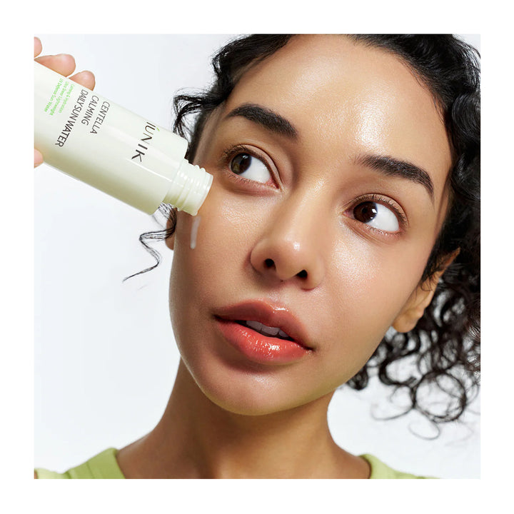 Woman applying skincare product to her face with a white background