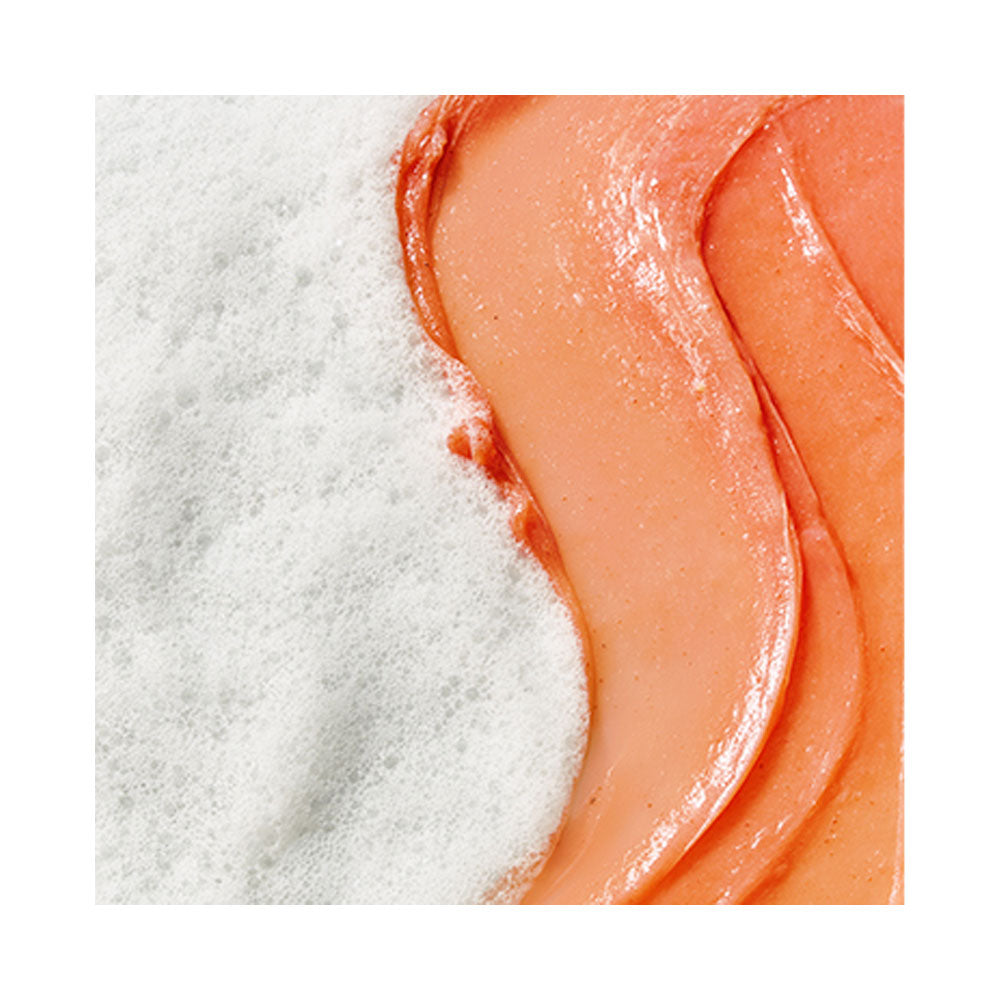 Close-up of pinkish-orange scrub and white sand on a white background