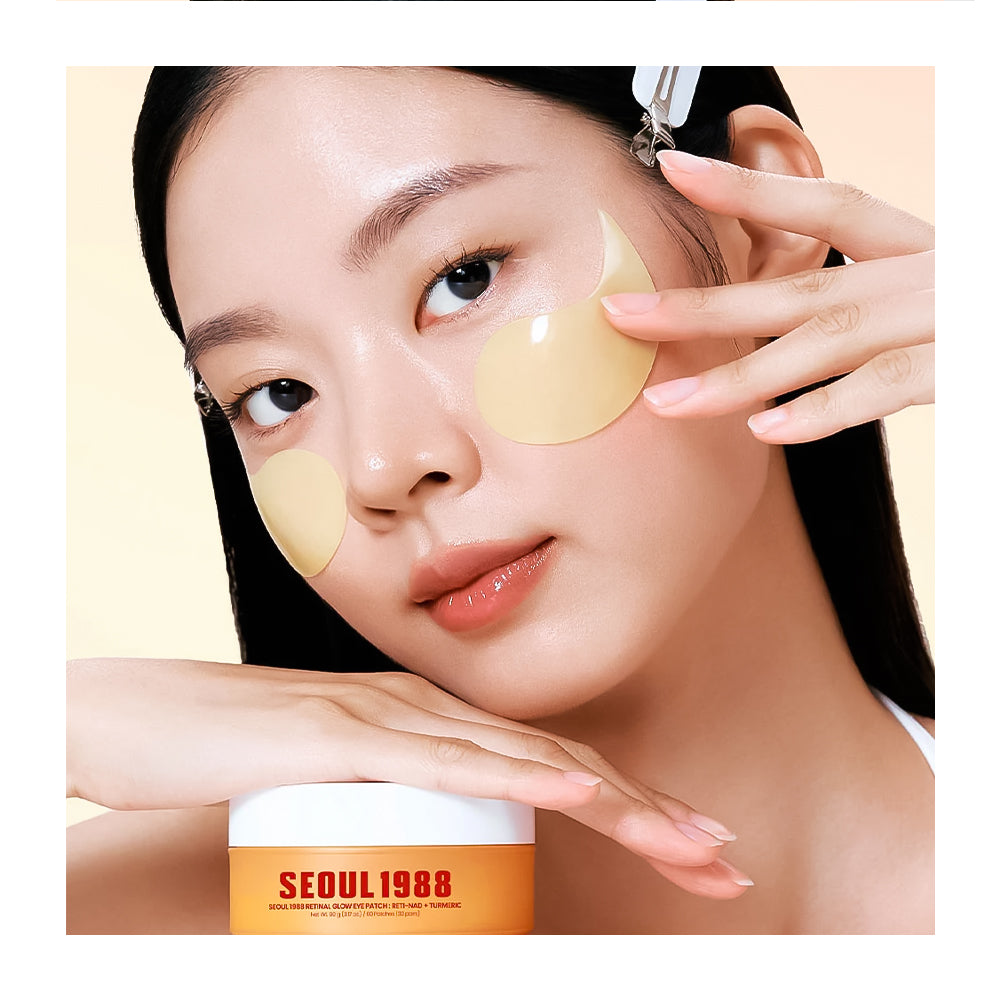 A close-up of a woman applying or wearing pale yellow crescent-shaped eye patches on her face, with her hand resting near the lower edge. A white and orange cosmetic jar labeled 'SEOUL 1988' is visible at the bottom.