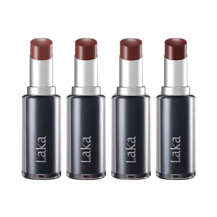 Four Laka lipsticks arranged in a row on a plain white background. Each lipstick has a dark translucent cylindrical case, a silver metallic neck, and a warm reddish-brown lipstick bullet exposed.