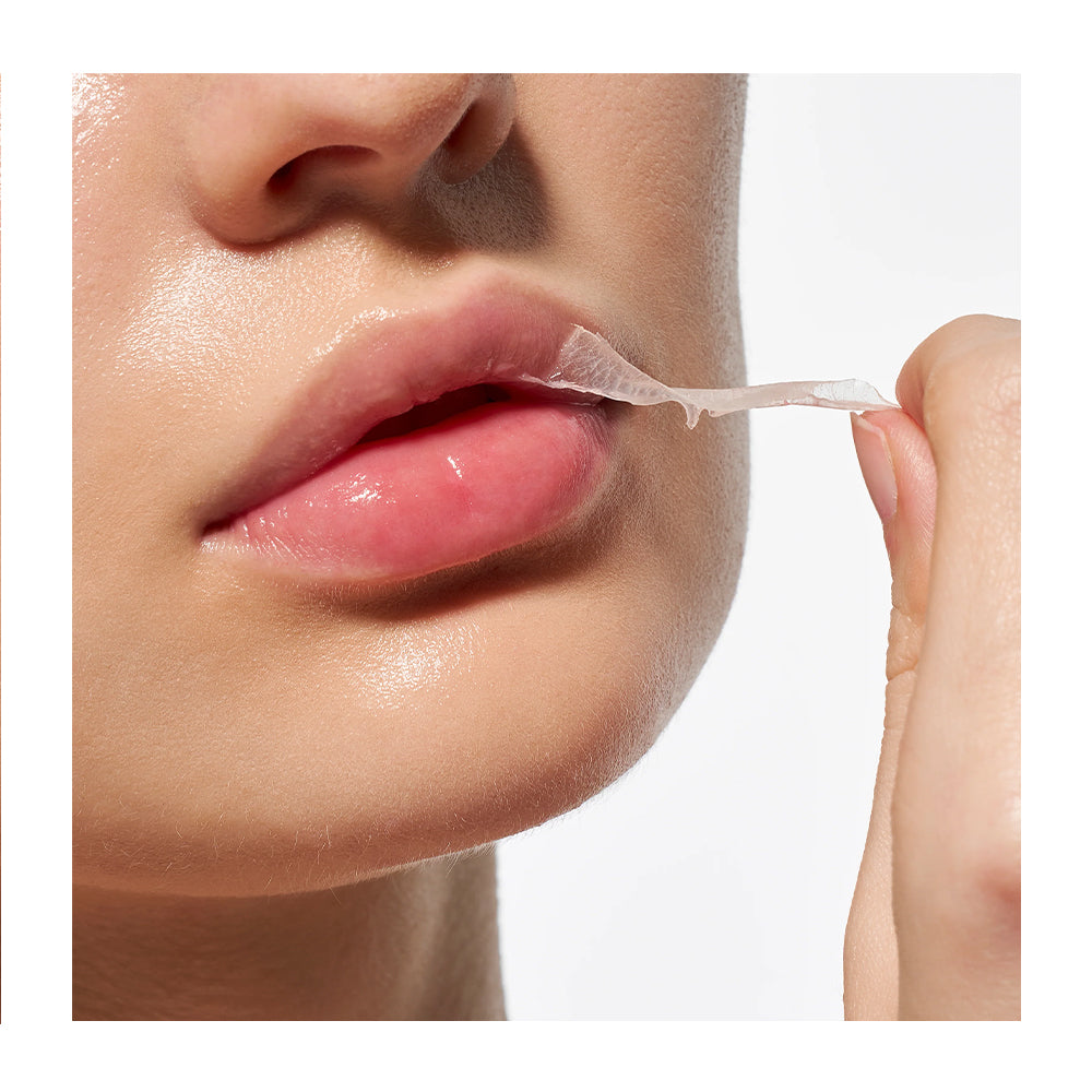 Close-up of a person peeling a translucent, skin-like lip mask or peel from their lips against a clean white background.