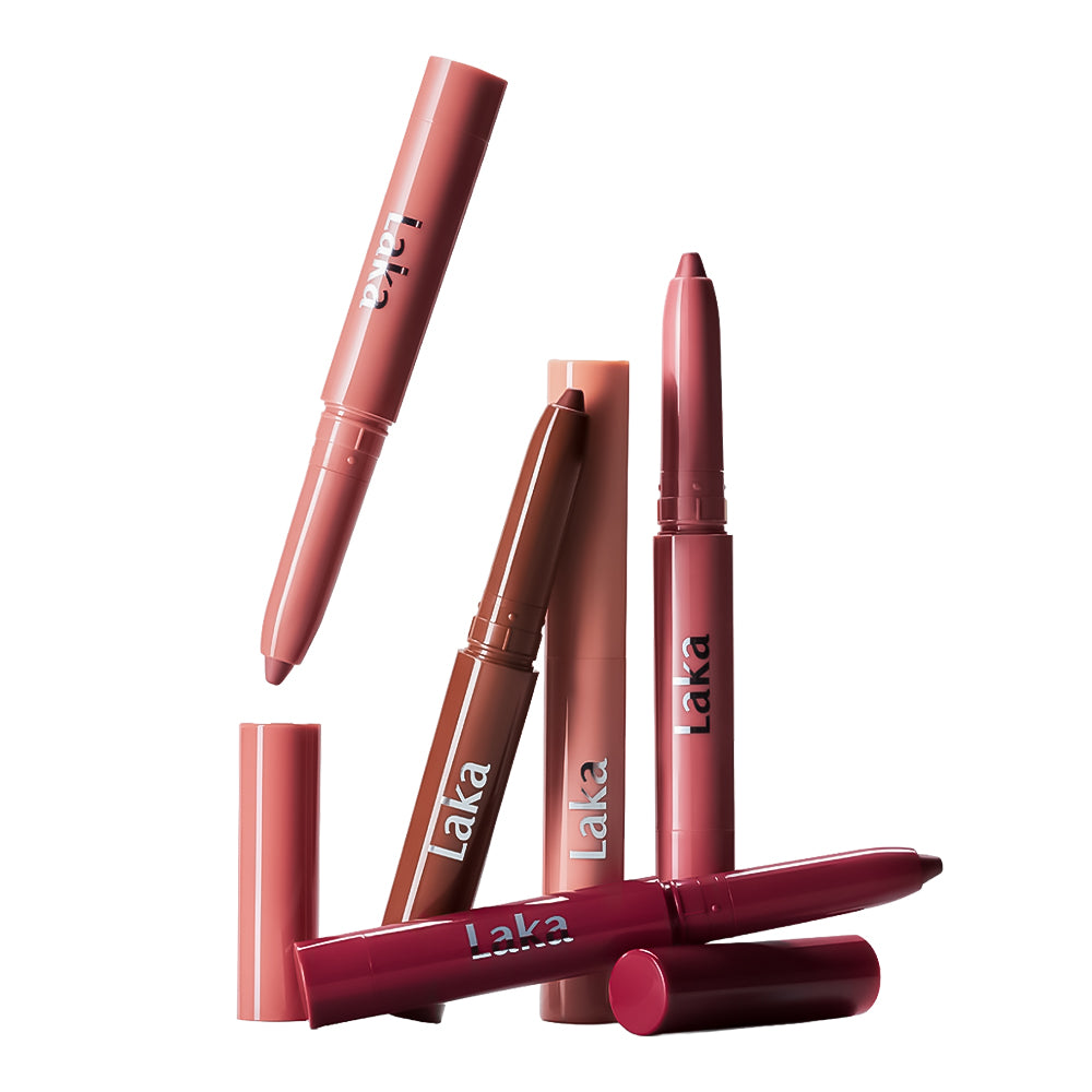 Six Laka lip color pencils in various shades, including nude pink, brown, and deep berry, arranged dynamically on a clean white background.
