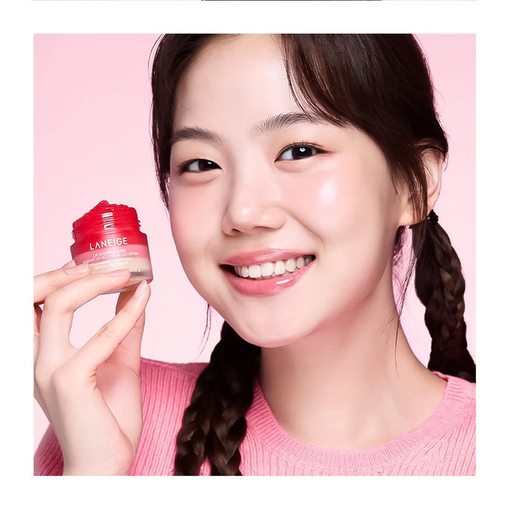 A smiling young woman with braided dark hair holds a small red cosmetic jar labeled LANSEIGE against a soft pink background.