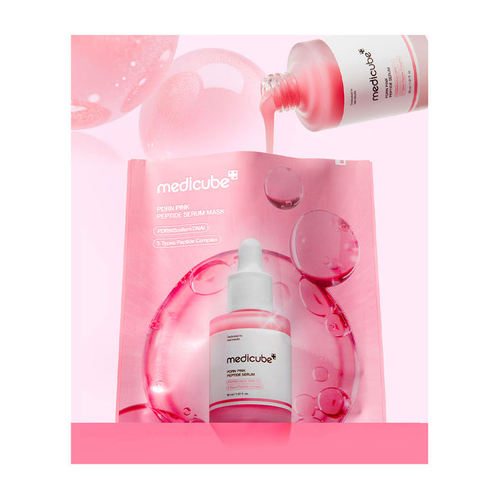 Medicube FRESH PINK Peptide Serum Wash shown with its pink outer packaging, a dropper bottle of pink serum in the foreground, and a second bottle pouring pink gel into a bubble-like shape above. The design uses pink liquid droplets and glossy bubble graphics on a pale pink background.