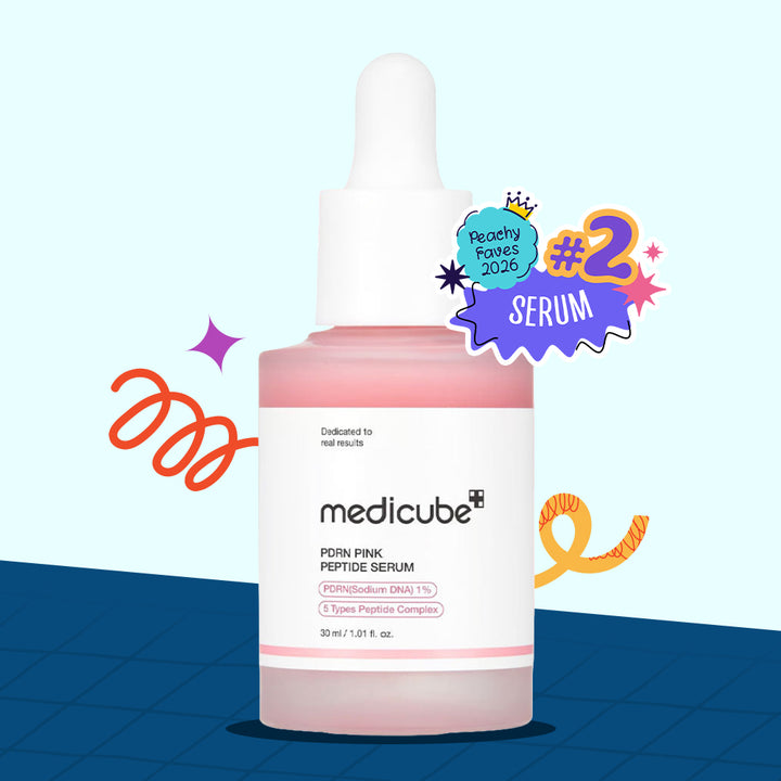 A bottle of medicube PDRN Pink Peptide Serum with a white dropper cap and a pink liquid visible inside, set against a light blue background with a dark blue grid at the bottom. A purple and blue &