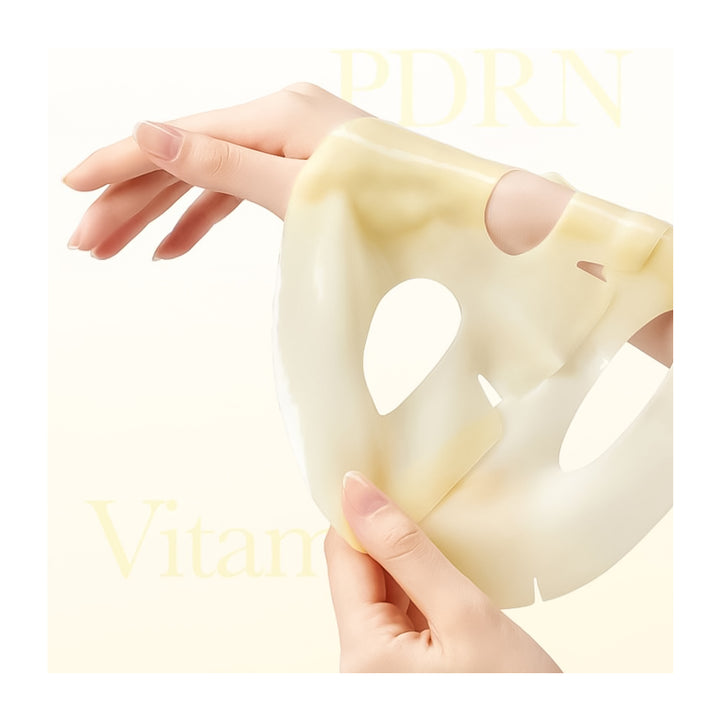 A translucent pale yellow silicone or rubber sheet with cutouts, held by two hands against a soft cream background with faint &