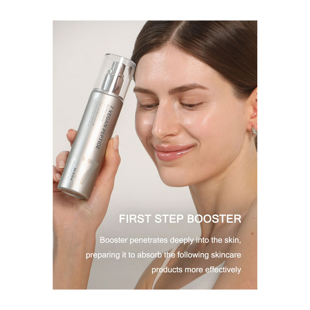 A woman holds a silver cylindrical skincare booster bottle near her face against a light neutral background, with text reading &