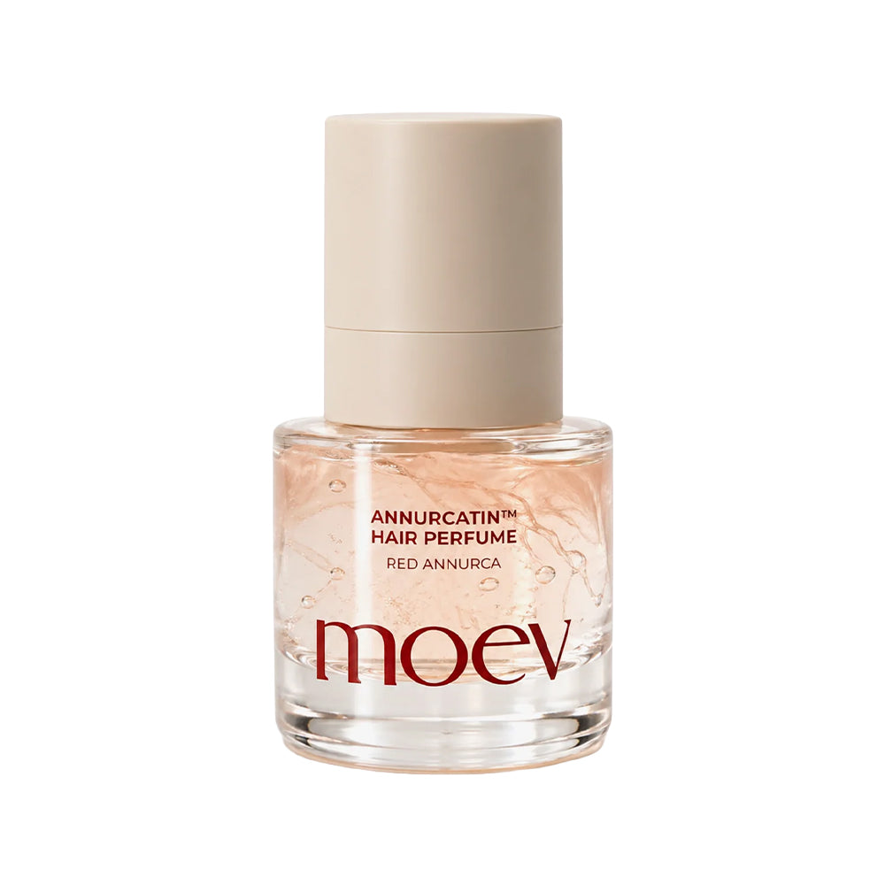 A bottle of moev Annurcatin Hair Perfume in Red Annurca, featuring a clear glass bottle filled with a pale pink liquid and a beige cap, on a white background.