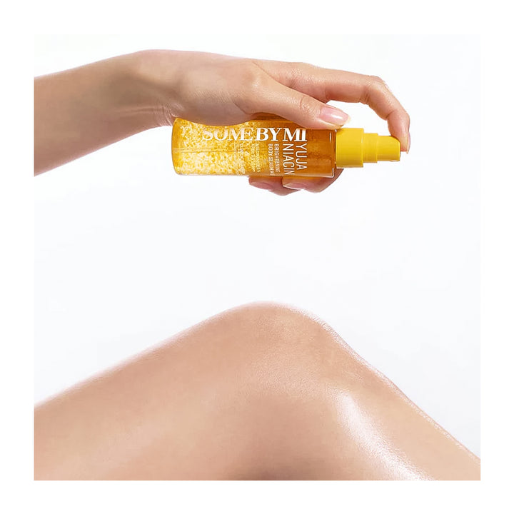 A hand holding a bottle of Some By Mi Ylia Magic Sunscreen Lotion against a white background, with a model&