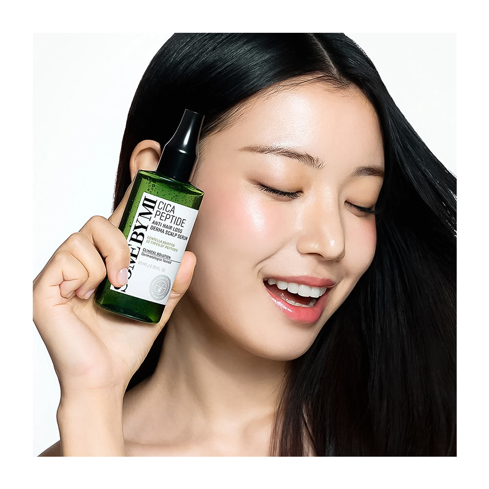 A woman with long black hair holds a green bottle of BYUMI Cica Peptide Multi-Functional Serum Treatment next to her face against a white background.