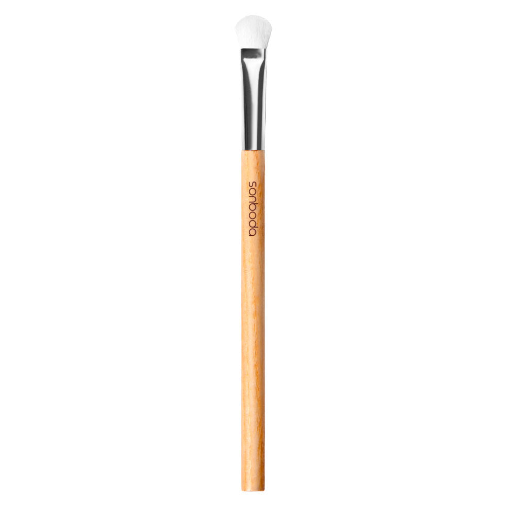 A single makeup brush with a light natural wood handle, a silver ferrule, and white bristles, shown vertically on a plain white background. The brand name 'DODOQUOS' is printed on the handle.