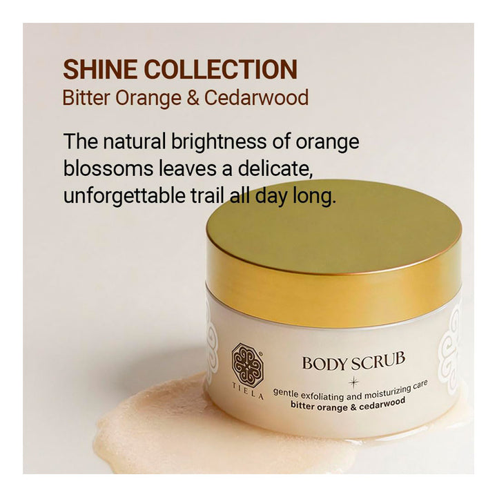 A cream-colored body scrub jar with a metallic gold lid from the brand YIELA, under the &