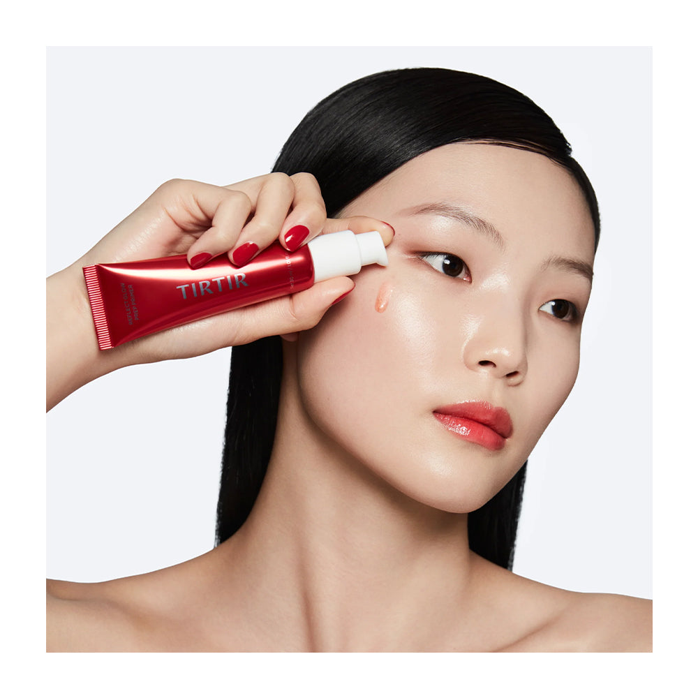 A woman with long black hair applies a red TIRTIR cosmetic cream from a red squeeze tube with a white pump dispenser. She is shown in a close-up profile against a clean white background.