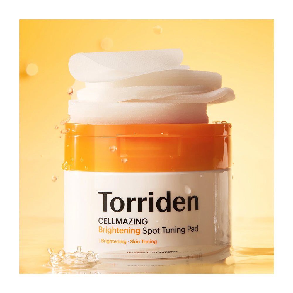 A jar of Torriden Cellmazing Brightening Spot Toning Pad with a white pump dispenser and an orange collar, set against a warm yellow background with stylized liquid droplets.