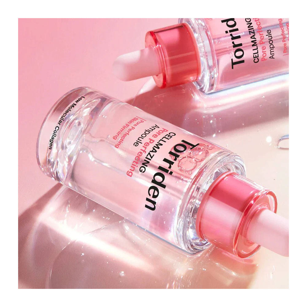 Two clear cosmetic dropper bottles with pink caps and pink liquid inside, labeled Torriden Cell-Maximizing Ampoule, arranged on a glossy pink reflective surface.