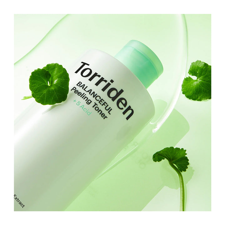 A bottle of Torriden Balancing Peeling Toner with a mint green cap, styled with green leaves on a light green background with a clear liquid splash.