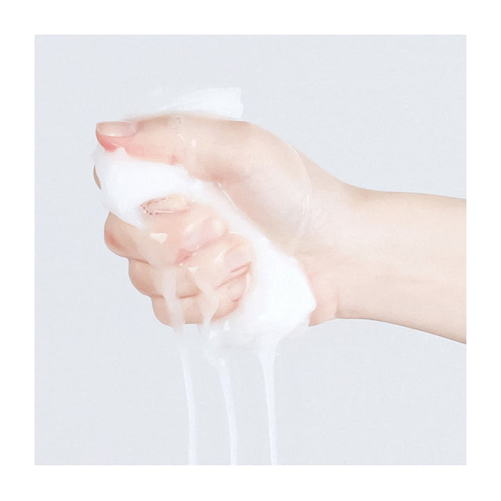 Hand squeezing a white fluffy substance against a light gray background