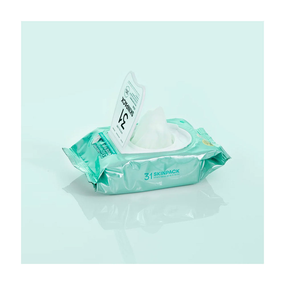 A pack of 31 SKINPACK facial wipes with a single wipe pulled out, set against a light mint green background with a soft reflection.