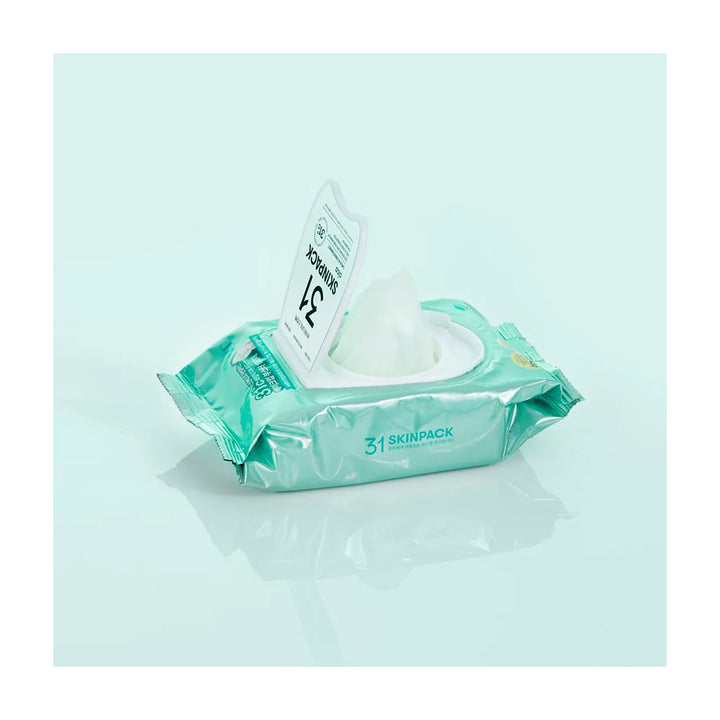 A pack of 31 SKINPACK facial wipes with a single wipe pulled out, set against a light mint green background with a soft reflection.