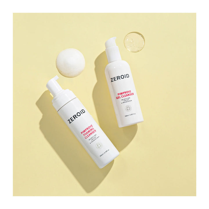 Two white pump bottles of ZEROID facial cleansers, one foaming cleanser and one gel cleanser, arranged diagonally on a pale yellow background with a white sphere and a clear gel droplet prop.
