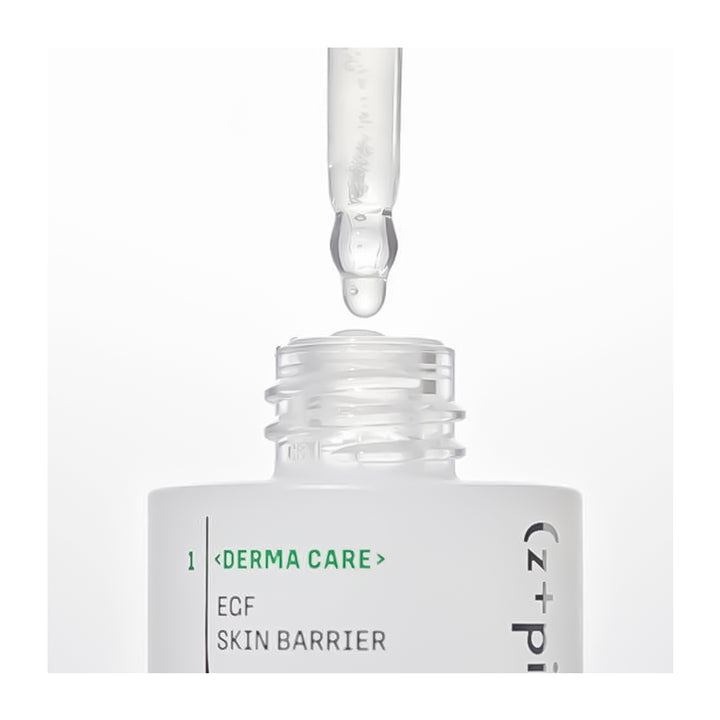 A close-up of a skincare dropper bottle with a clear glass pipette above the open bottle, showing a clear serum drop. The label reads &
